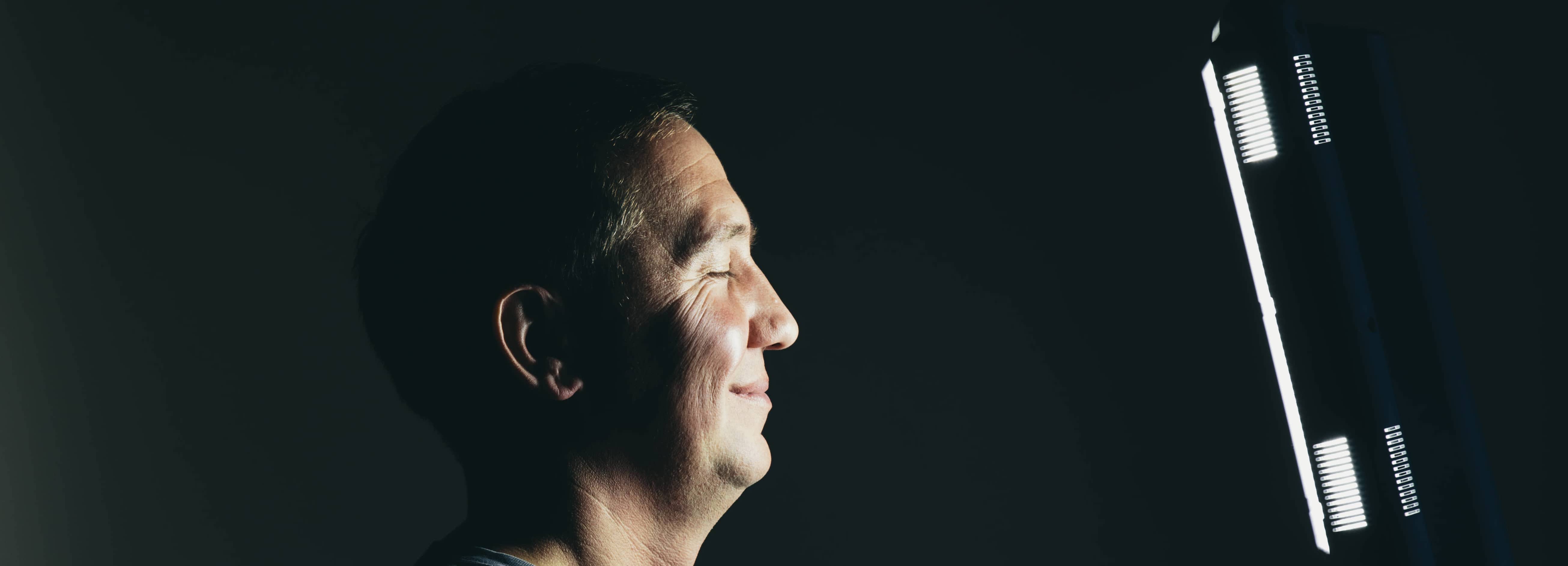Smiling middle aged man sitting in front of a light therapy box