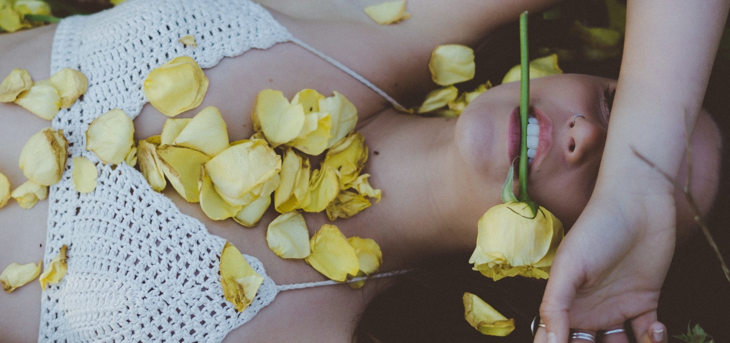 Woman laying down on the ground, covered with flowers