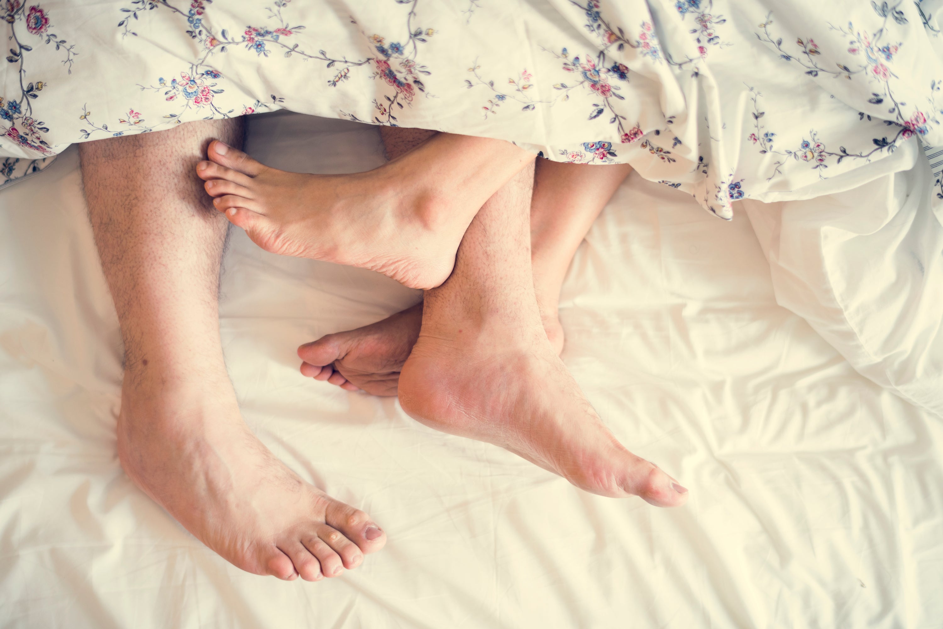 Overhead view of feet sticking out from under a blanket