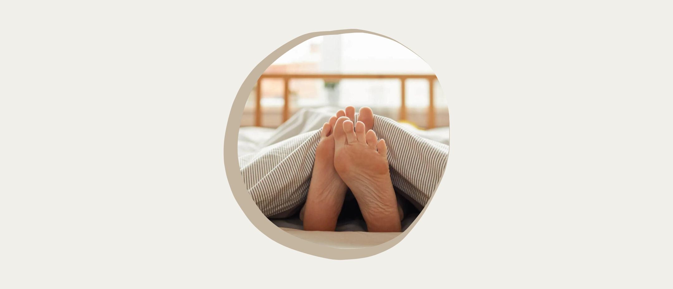 Close-up of a woman with bare feet lying under the blanket in bed