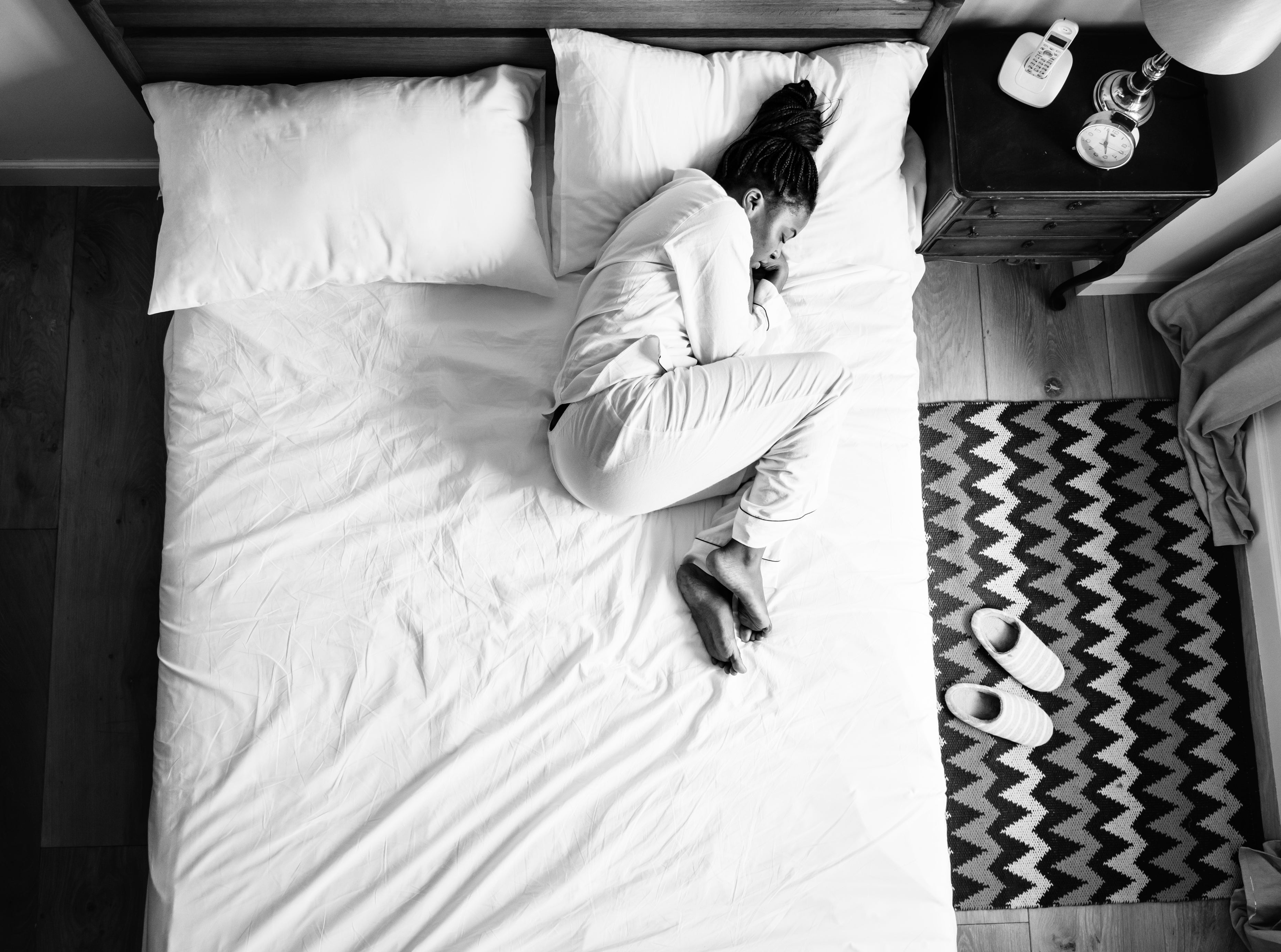 Lonely woman on curled up upon herself on her bed 